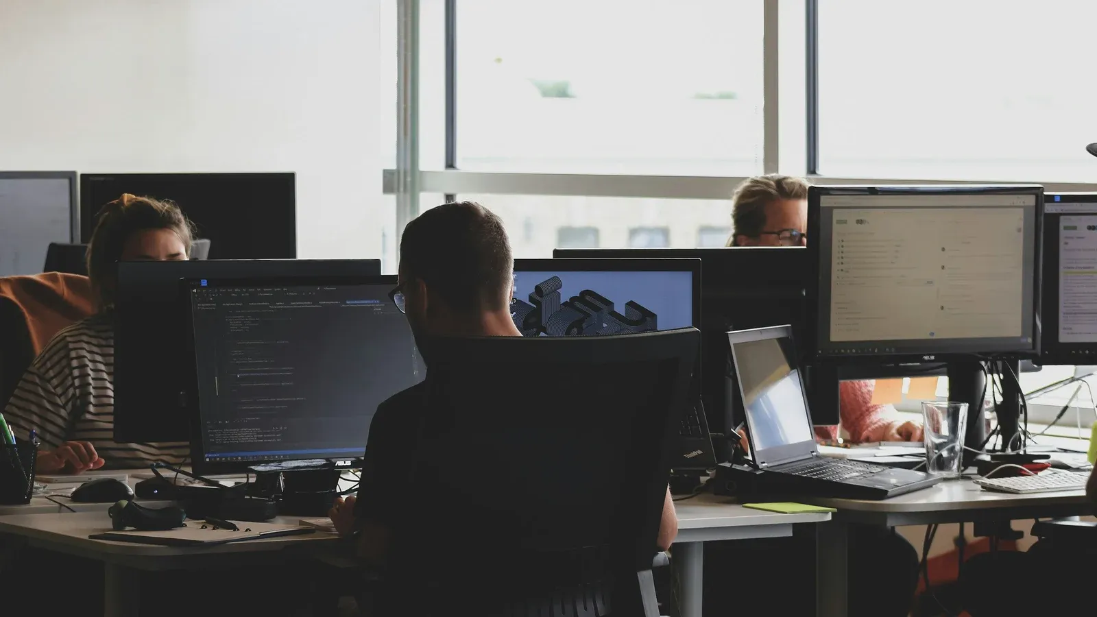 Engineers working at multiple monitors in an open-plan office