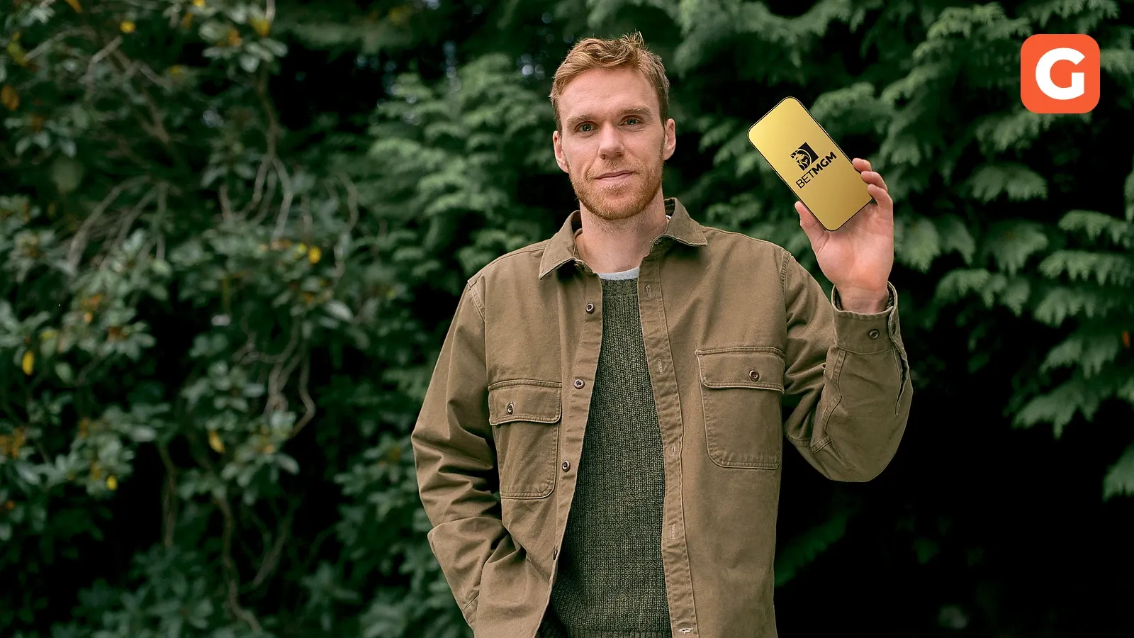 Connor McDavid holding a phone showing the BetMGM logo
